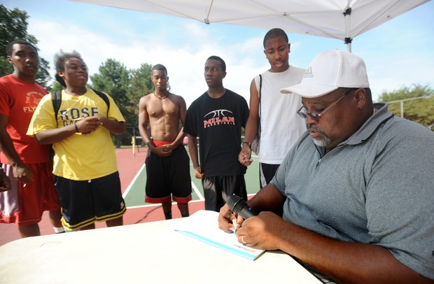 Harold Wimberly, right, who is a pastor at Christian Love Fellowship church located in the Washington Square neighborhood in Superior Township, writes down teams for the three-on-three Ballin' on the Boulevard basketball tournament held this past Wednesday evening at the tennis courts across from Cheney Academy in Superior Township. Angela J. Cesere | AnnArbor.com 